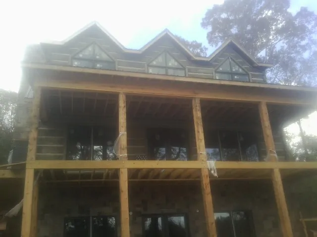 Dormers and porch framing on a large log home under construction — Roof Coating work by our crew in New Waterford