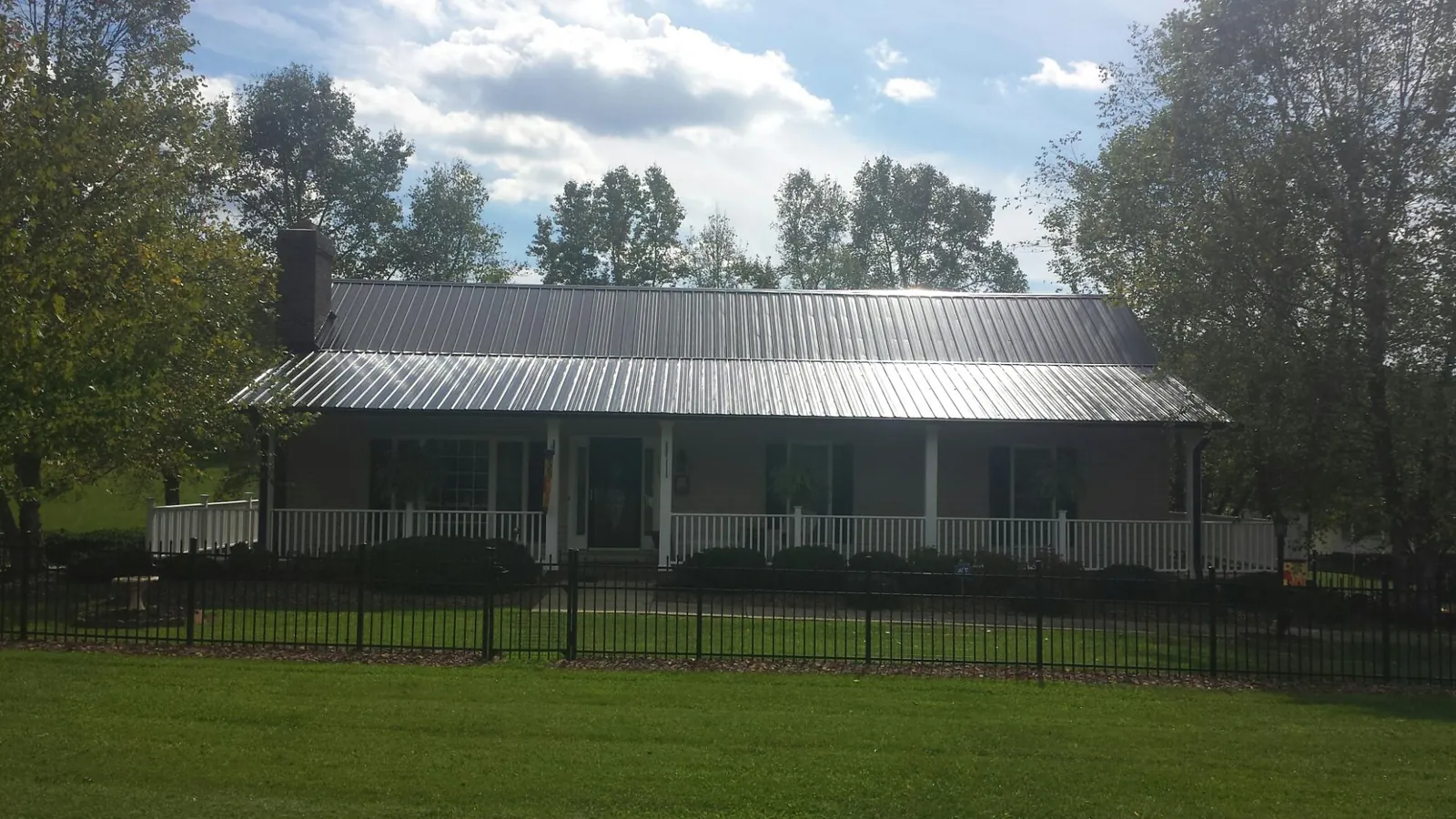 Gray metal roof on a brick ranch with a full width front porch — Gutter Guard Installation work by our crew in New Waterford