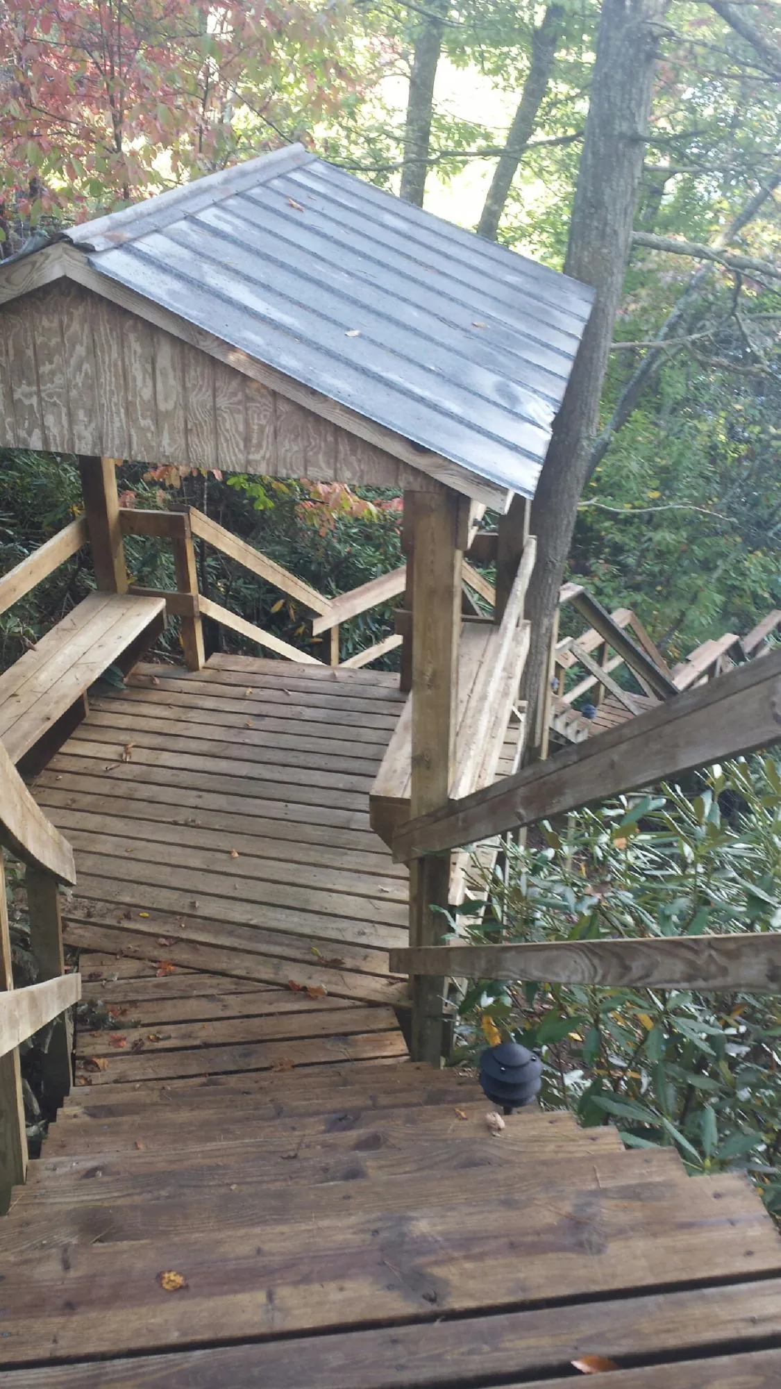 Metal roofed shelter over wooden steps on a wooded walkway — Skylight Repair & Installation work by our crew in New Waterford