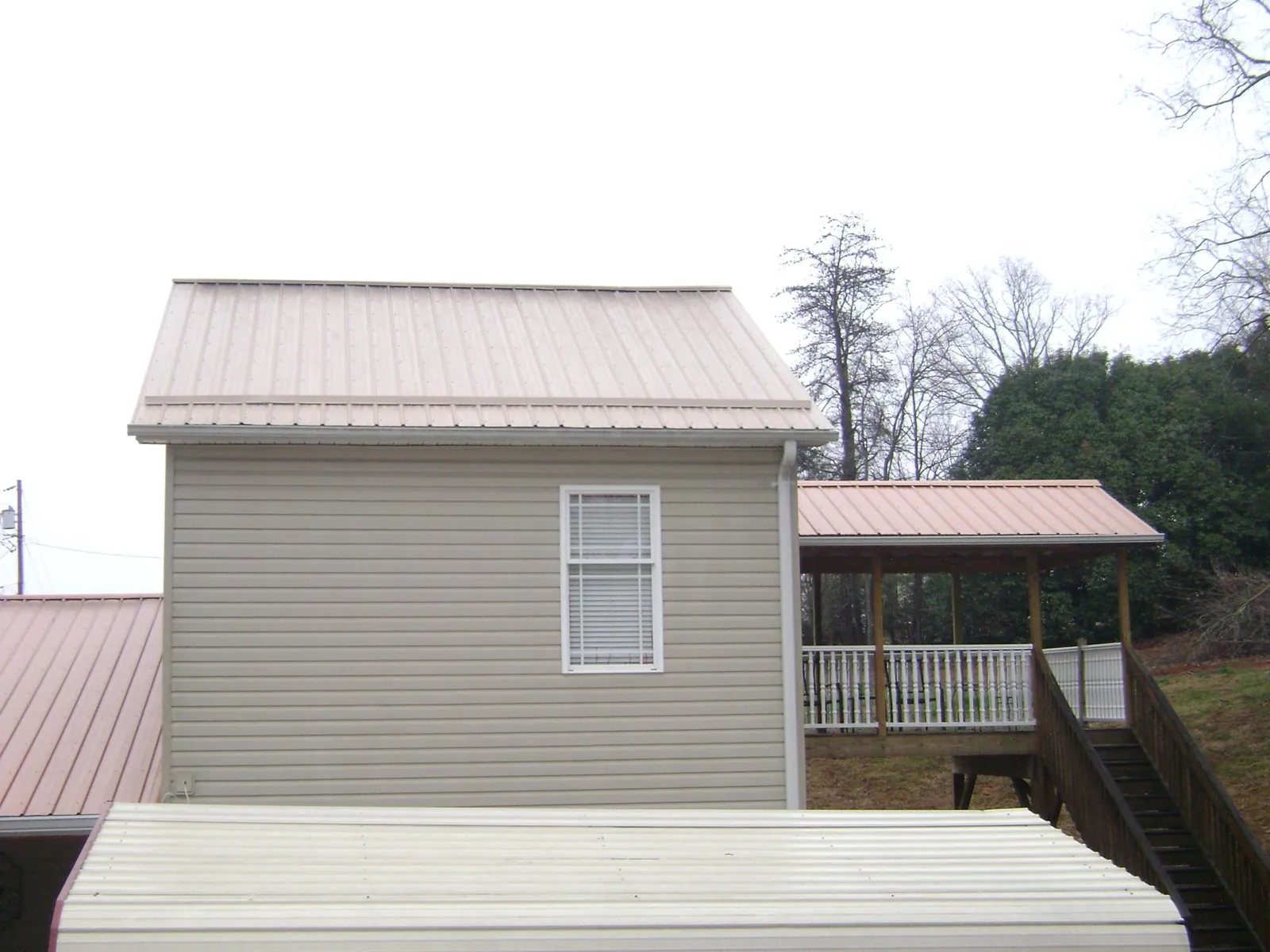 Tan metal roofs on a two story addition and attached porch, from a Roof Replacement job in New Waterford