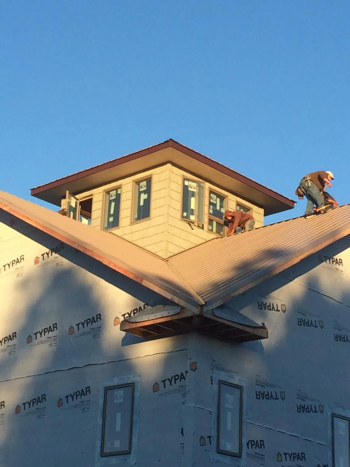 Roofers working around a rooftop cupola on a new metal roof at sunset — Roof Waterproofing in New Waterford by Roofing Brothers